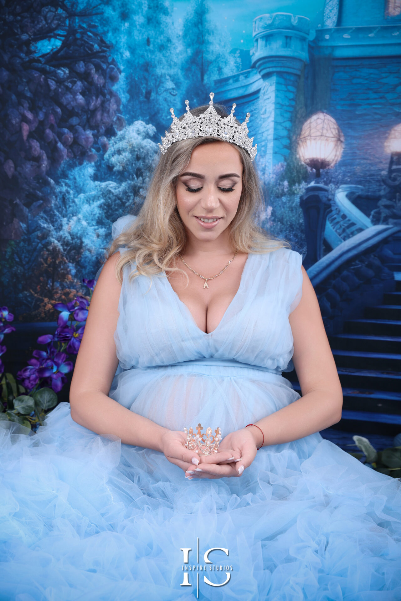 Pregnant woman in a sparkly blue dress in studio