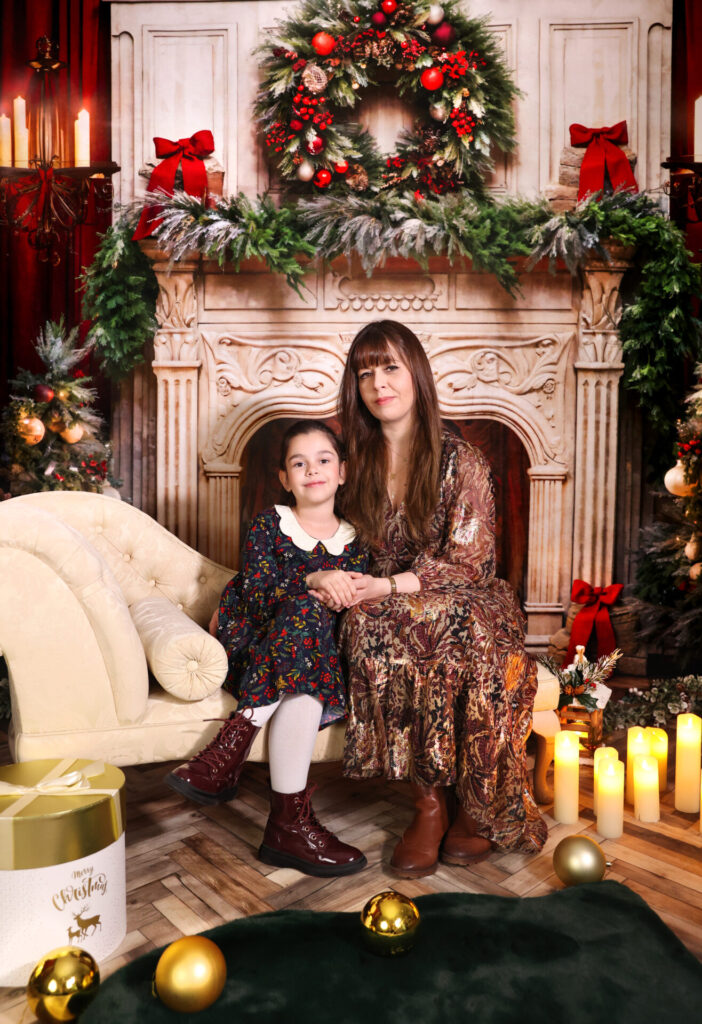 A cozy Christmas room with a classic fireplace, Christmas tree, and traditional red and green decorations.