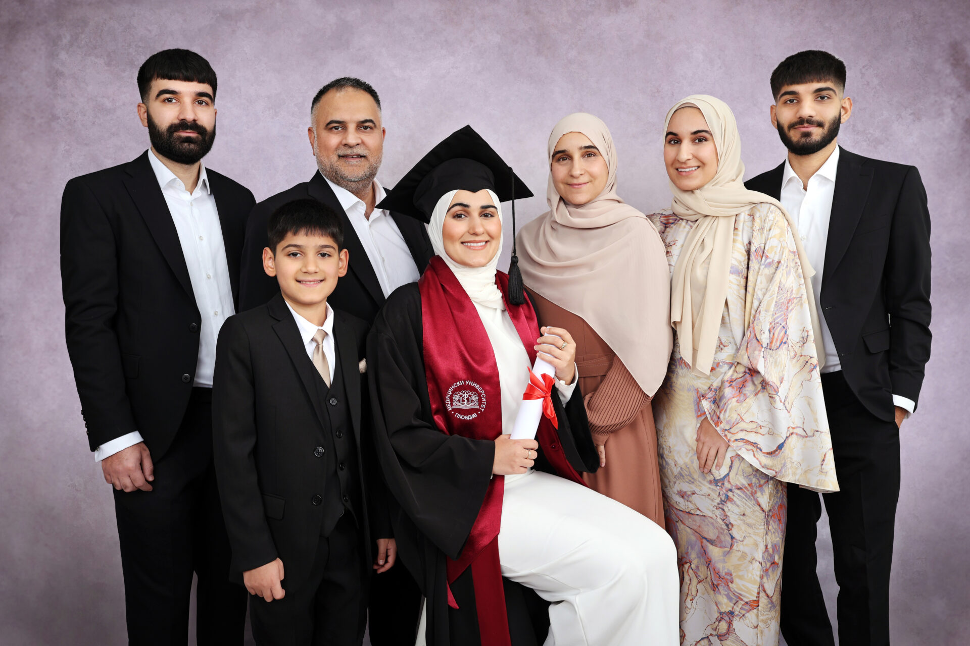 A family during graduation photoshoot London session with gown, mortarboard and hat.