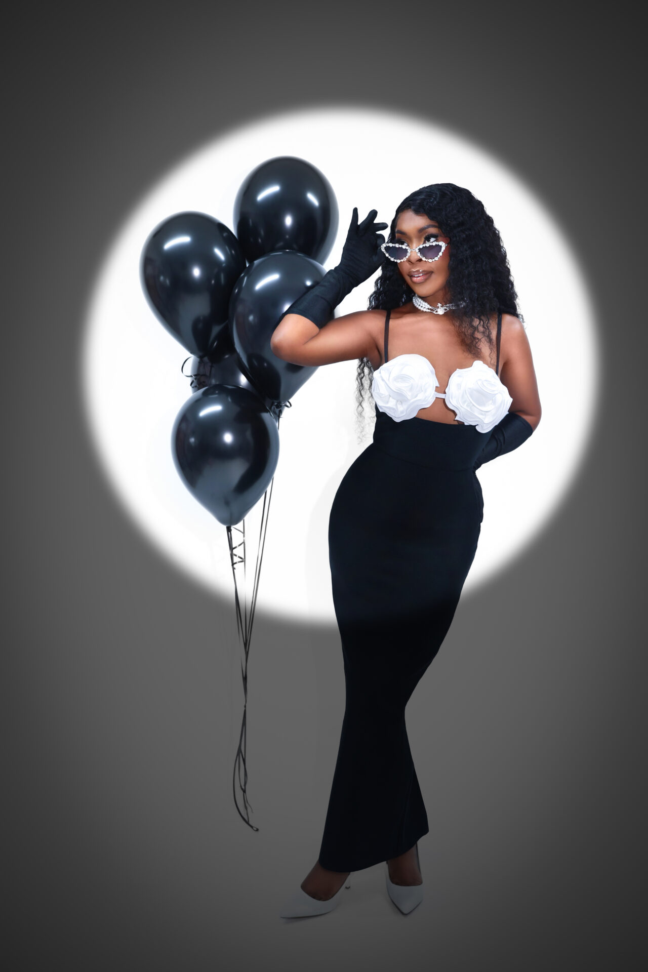 Woman posing with a cake and balloons during a custom birthday photoshoot.