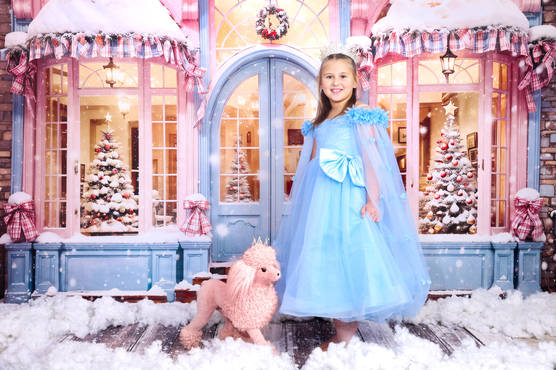 Girl dressed in blue dress captured in festive pink decor in studio.