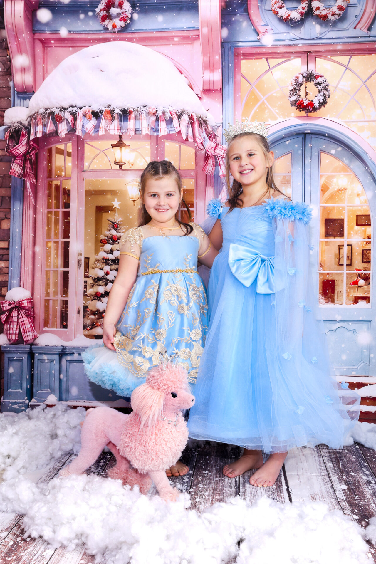 Two sisters dressed in blue dresses with a pink dog captured in festive pink decor in studio in Walthamstow.