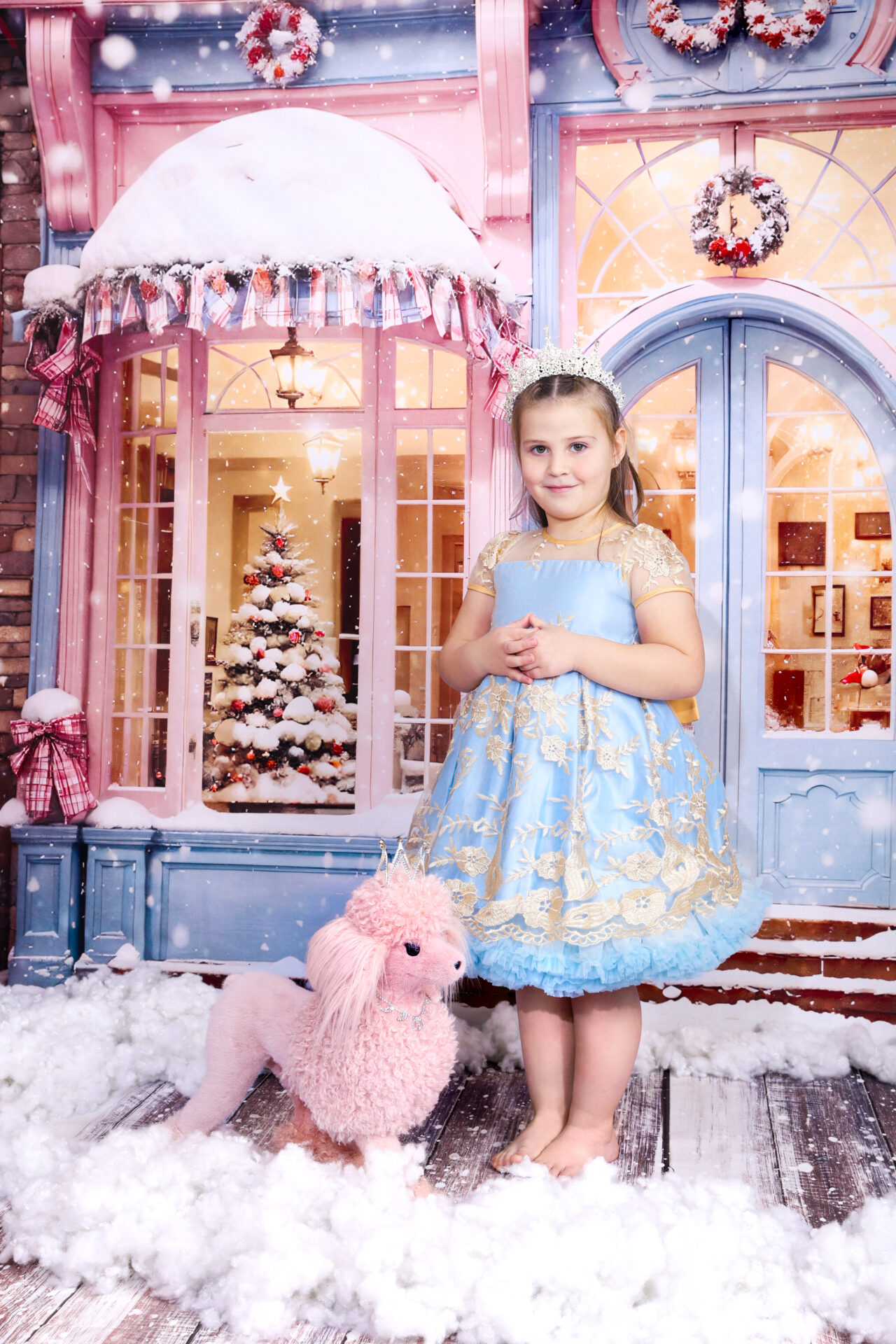 Girl dressed in blue dress with a pink dog captured in festive pink decor in studio.