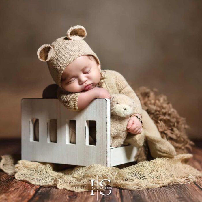 A newborn photo of a newborn sitting in a bed captured by female newborn photographer in London studio.