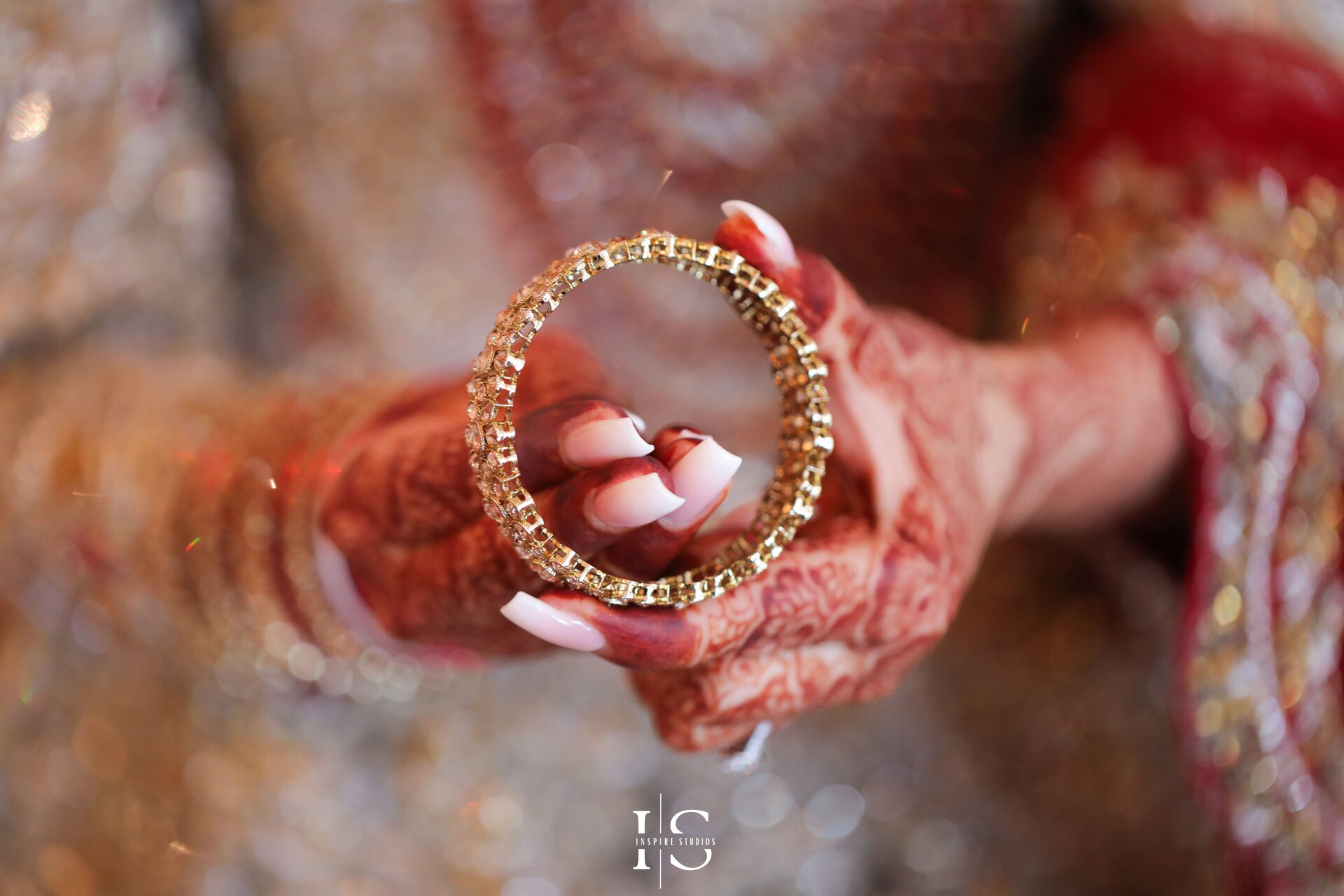 Close-up of a South Asian bride's hands adorned with intricate mehndi and red-and-gold bridal bangles.