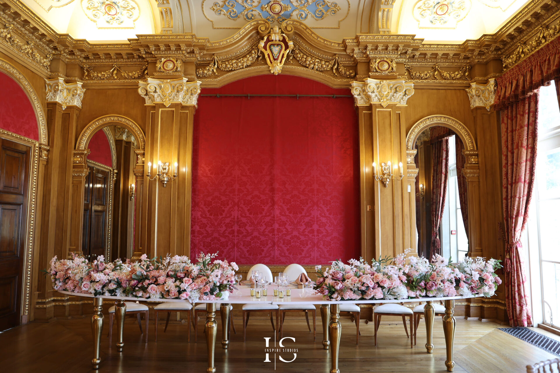 Grand London wedding venue with golden drapes and floral centerpieces set for a baraat ceremony.