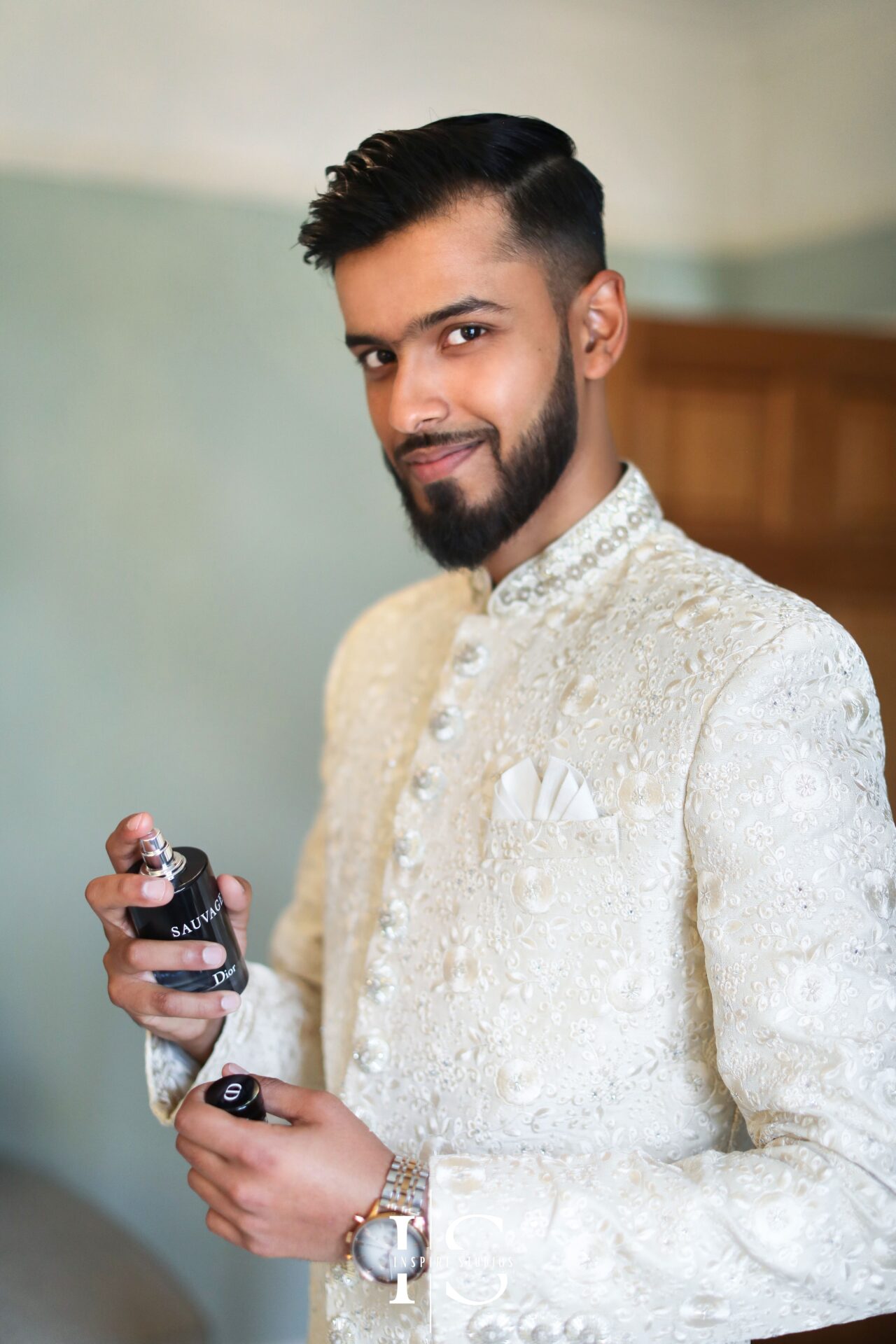 Baraat photographer in London capturing groom getting ready holding a bottle of perfume in hand.