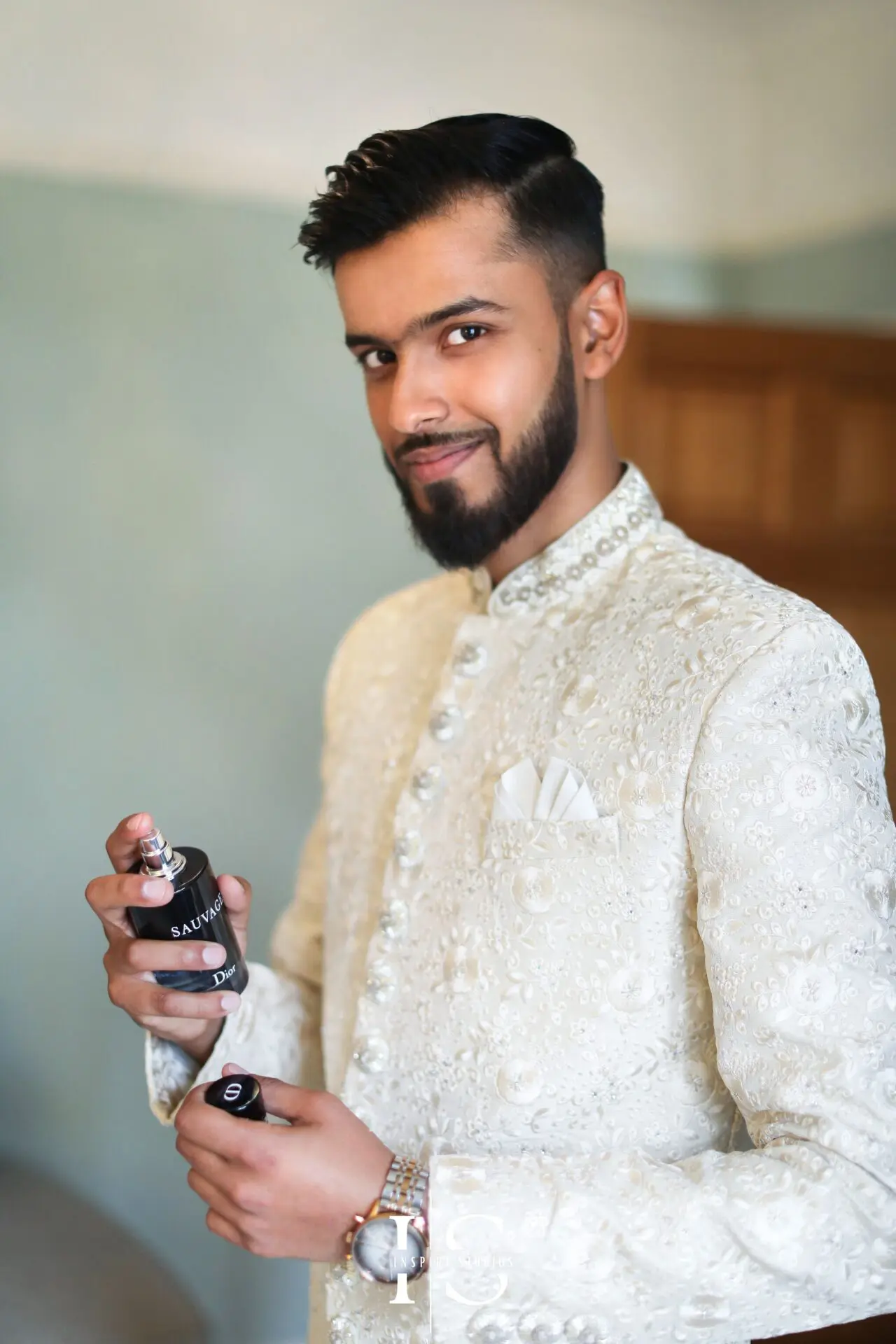 Baraat photographer in London capturing groom getting ready holding a bottle of perfume in hand.