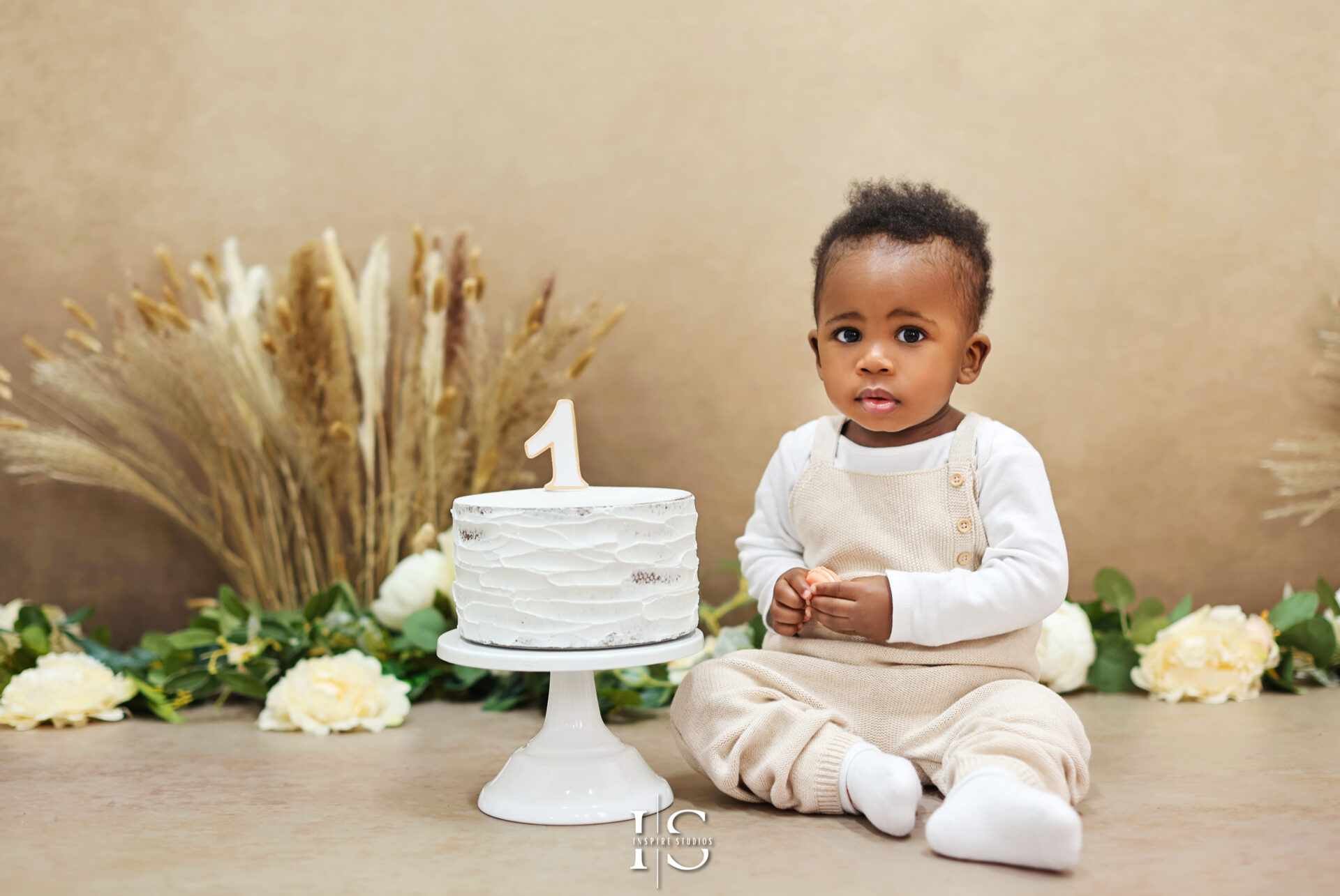 Smiling baby celebrating first birthday with cake smash in London studio.