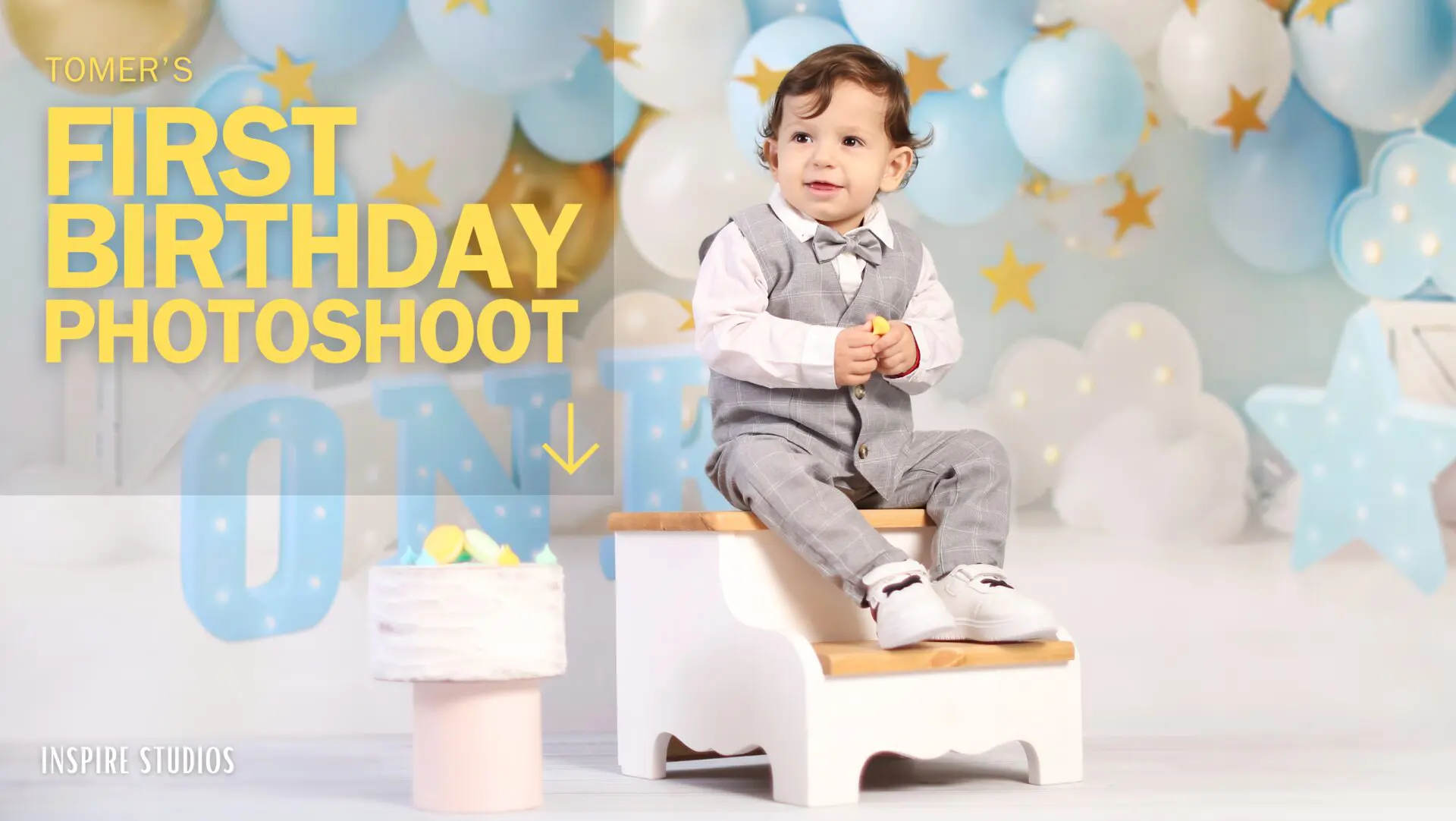 Toddler sitting in a cloud-themed first birthday photoshoot setup with 