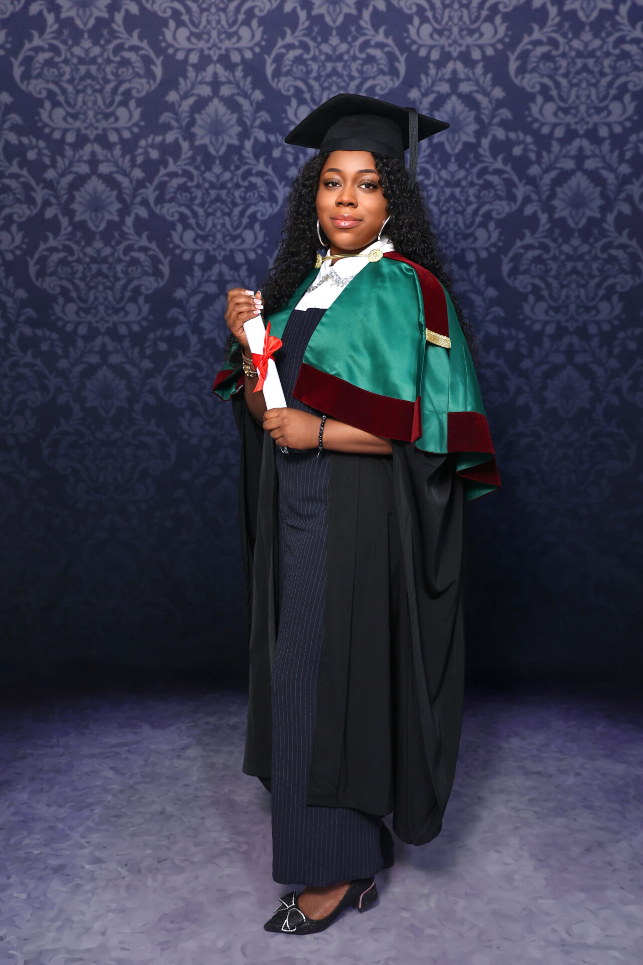 Graduate posing with cap and gown by a professional graduation photographer near me.