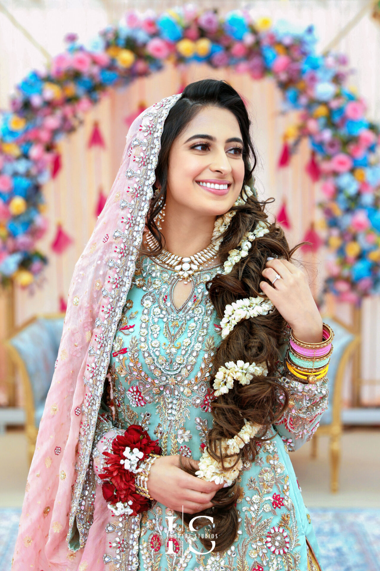 Luxury Asian wedding photography capturing a stunning bride in intricate attire and floral jewelry, set against a vibrant Mehndi backdrop in London.