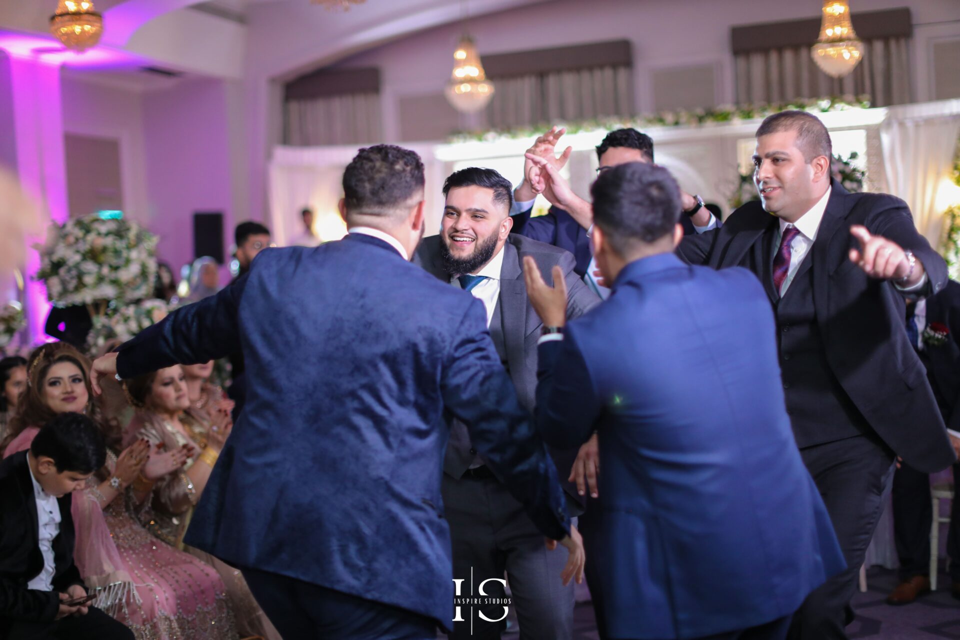 Walima wedding photographer in London capturing groom with family and friends laughing.