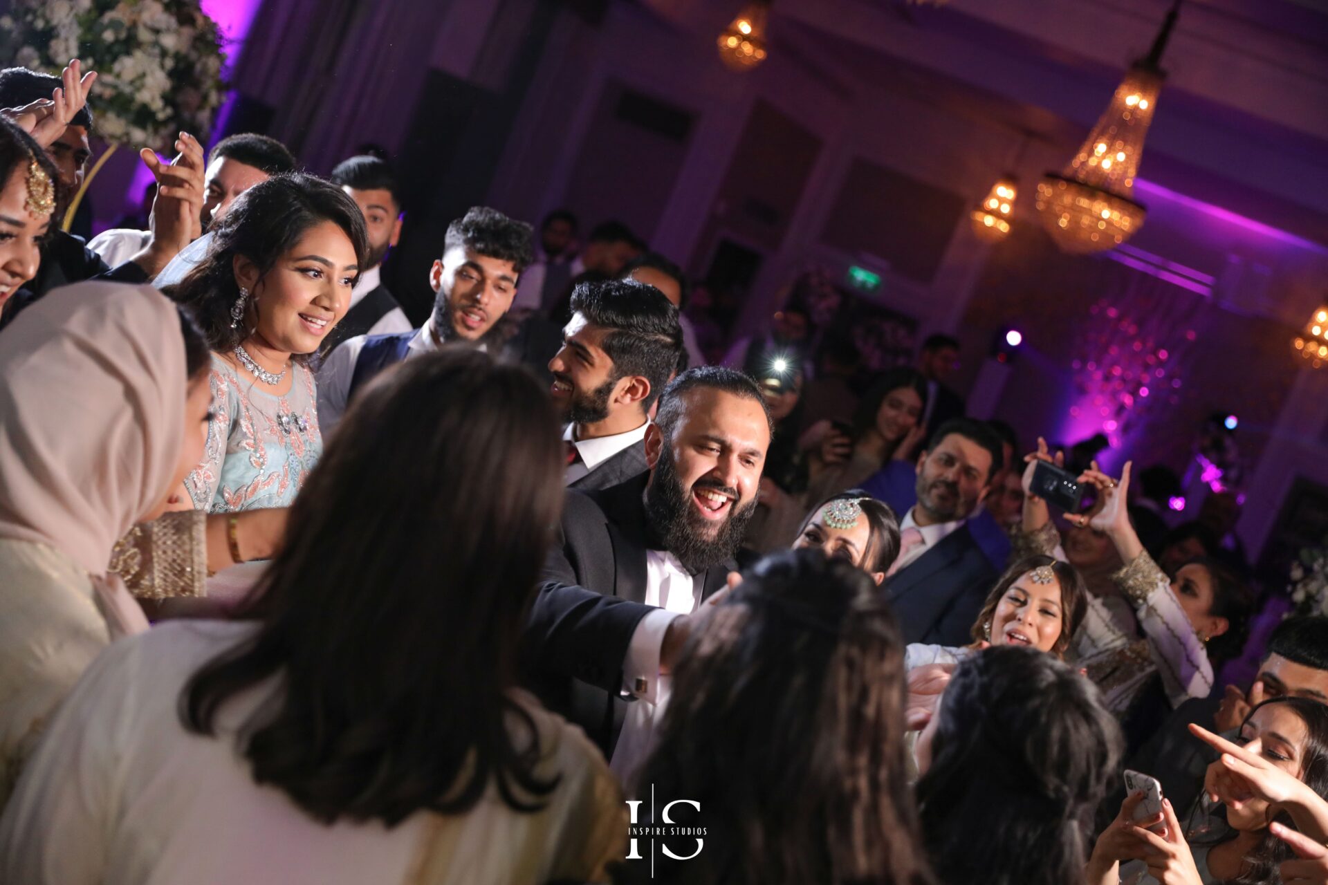 Walima wedding photographer in London capturing groom with family and friends dancing.