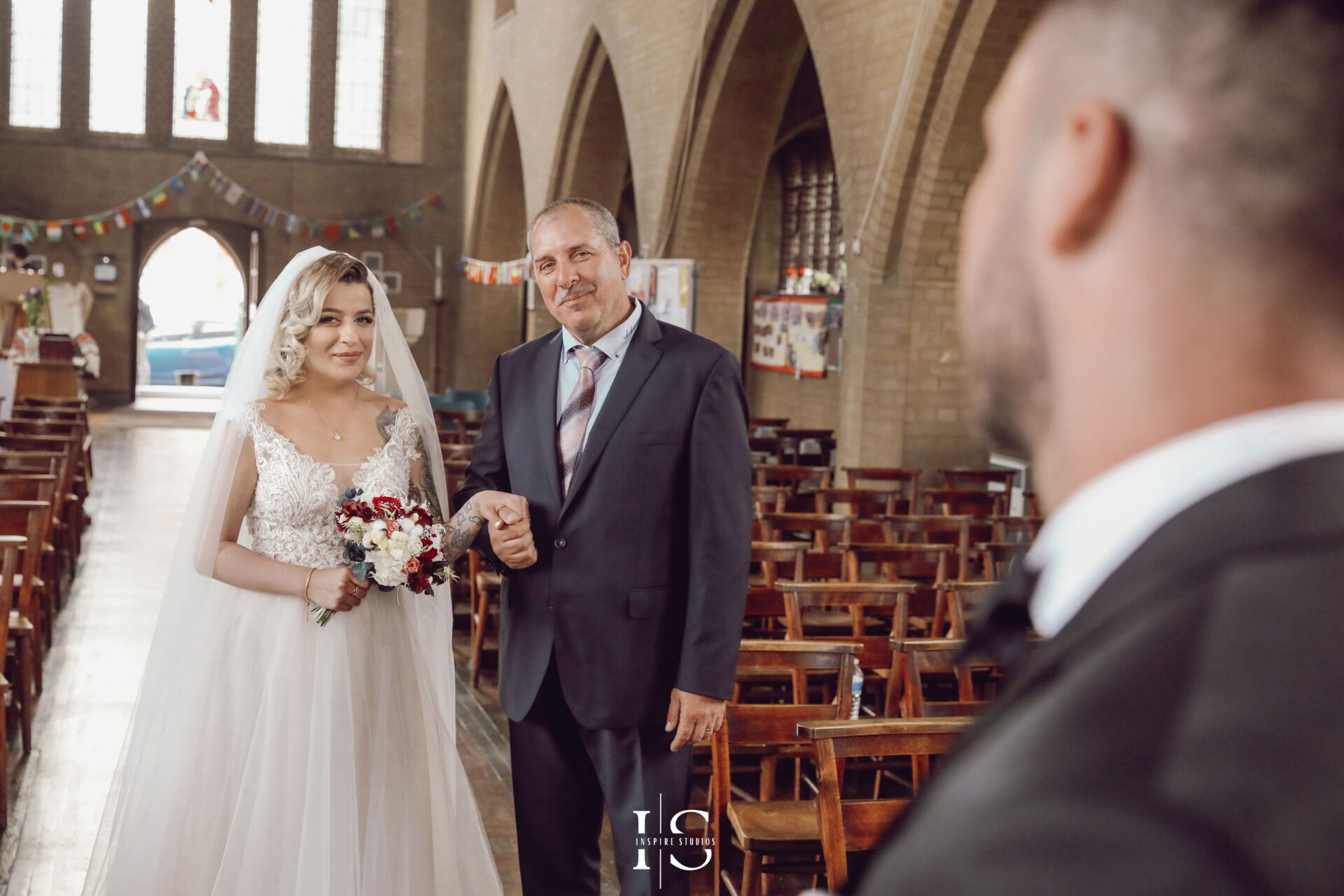 Wedding photography at church in London of bride in elegant white dress along with her dad in church.