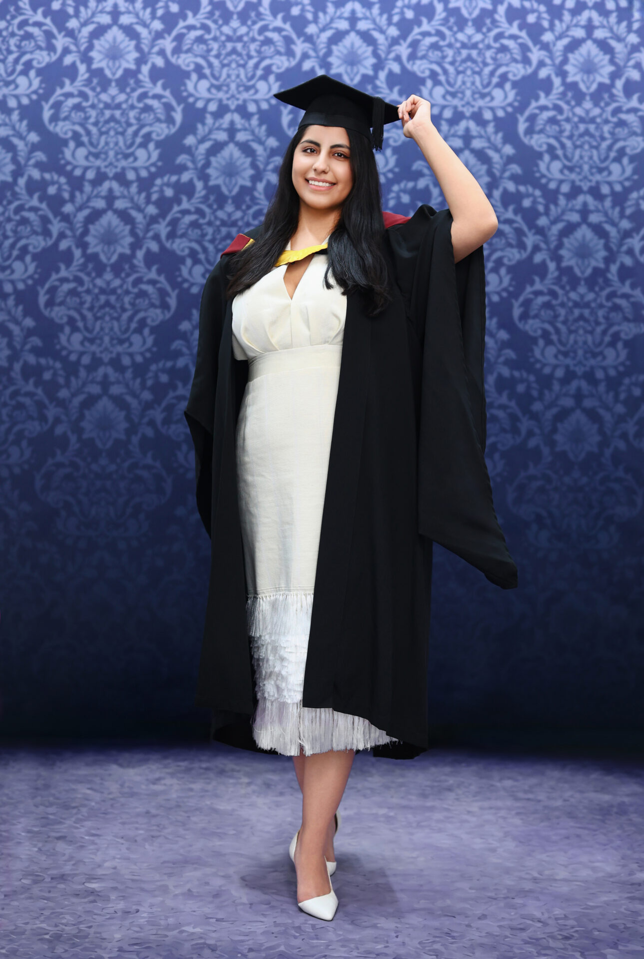 Graduate in cap and gown posing in a London studio for a professional graduation portrait