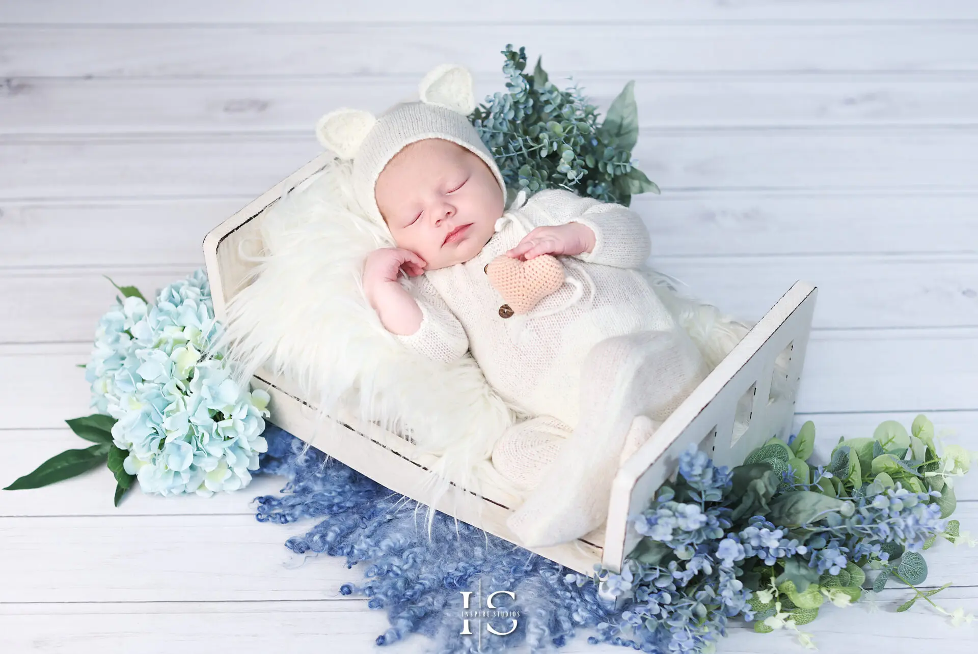A three-week-old newborn baby wrapped in a soft blanket during a London photoshoot.