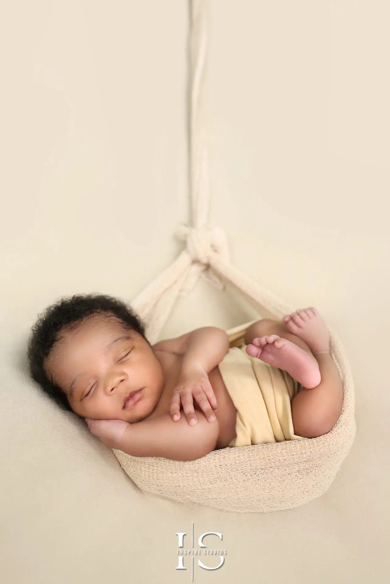 Newborn baby boy in a gentle sleeping pose on a fluffy blanket.