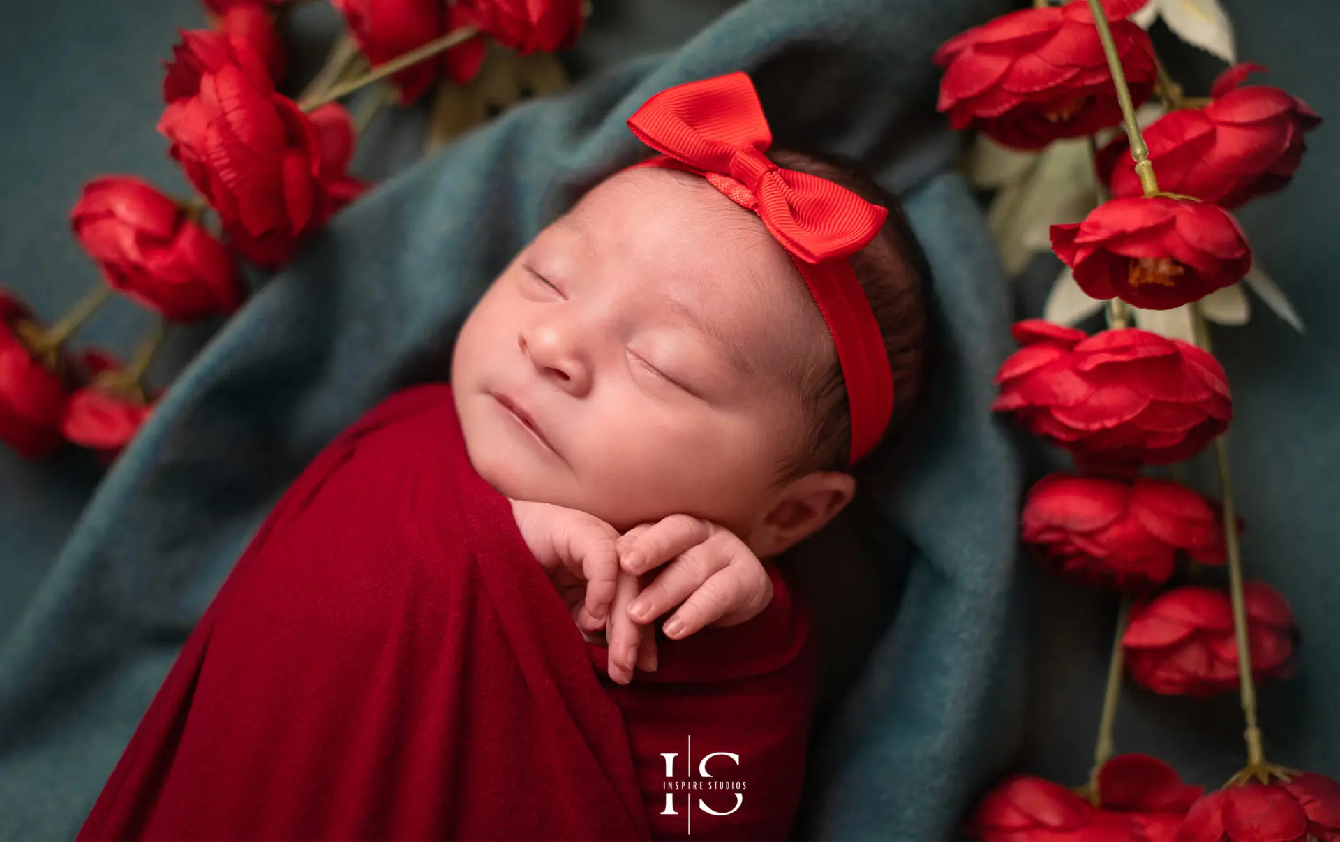 Newborn baby girl in a cozy pose wrapped in a pink blanket.