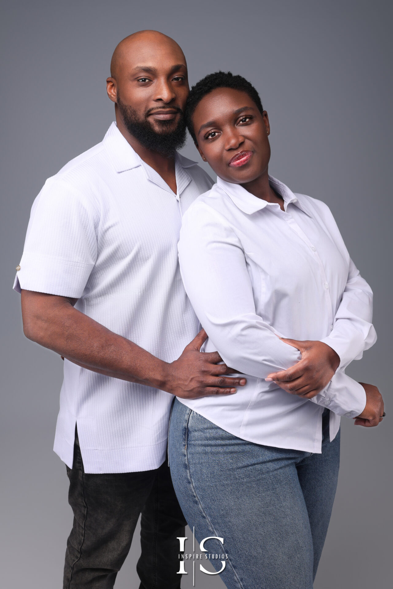 A stylish couple poses elegantly in a professional London studio, captured in soft, romantic lighting.