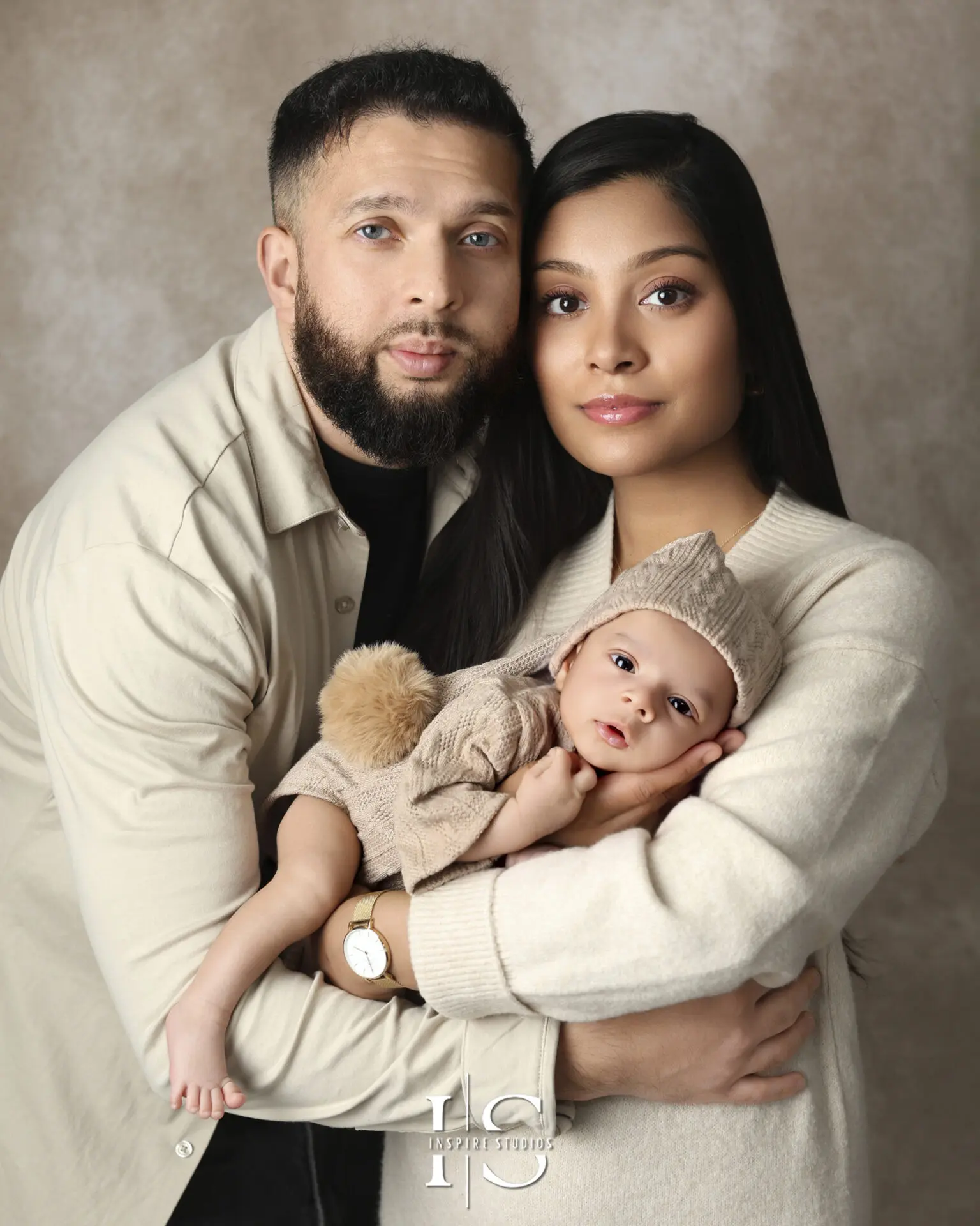 A loving family posing with their newborn in a cozy London studio, capturing their first moments together.