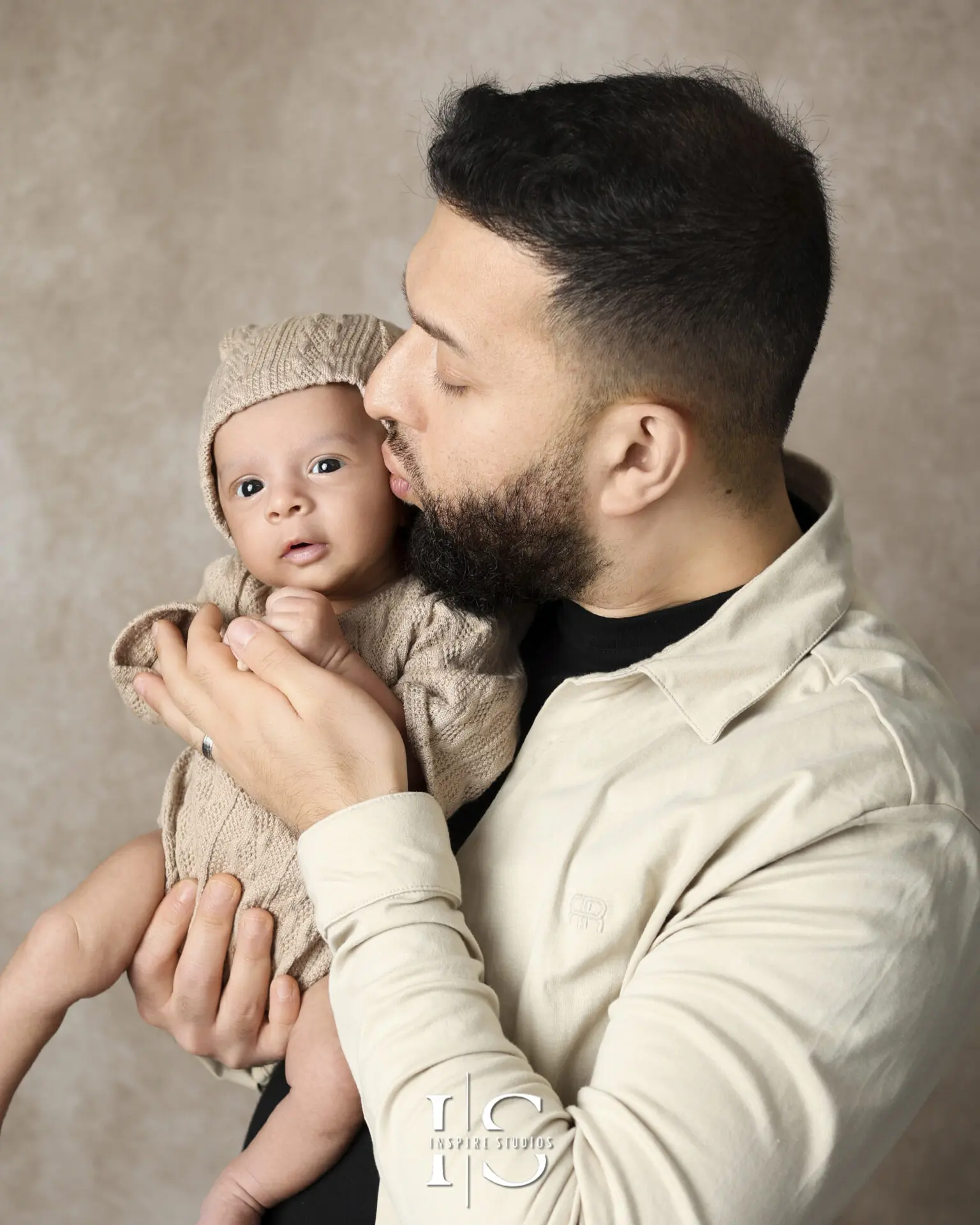 A newborn wrapped in a soft blanket, peacefully held by loving parents in a London-based photoshoot.