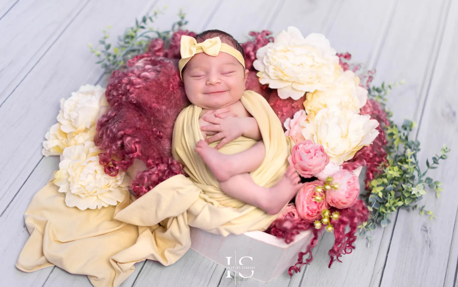 One-week-old newborn baby girl wrapped in a soft pink swaddle.