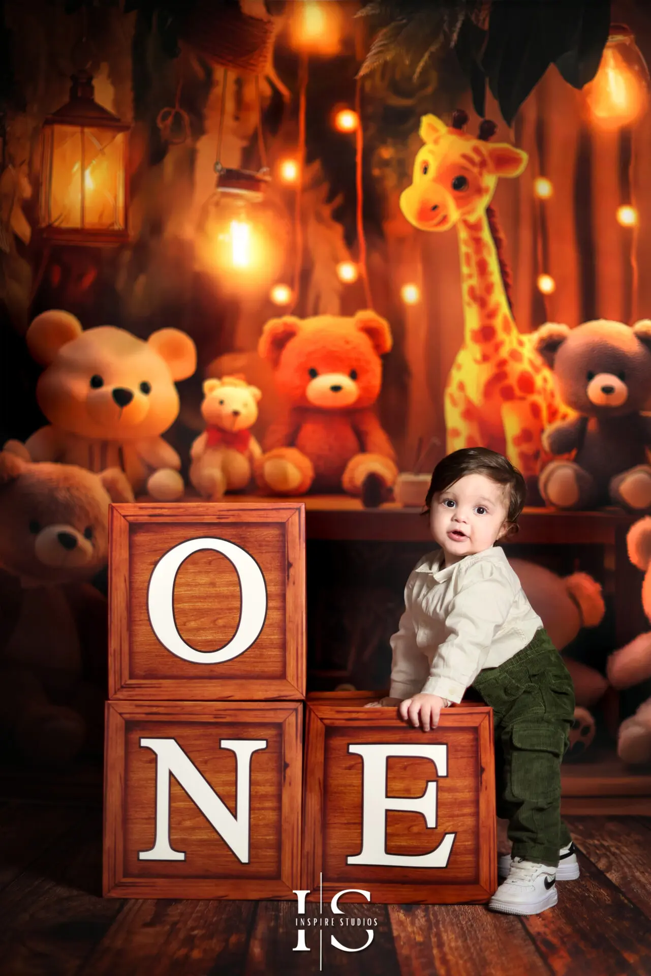 Smiling one-year-old during a Wild & One first birthday photoshoot with a jungle-themed cake and greenery backdrop in a London studio.