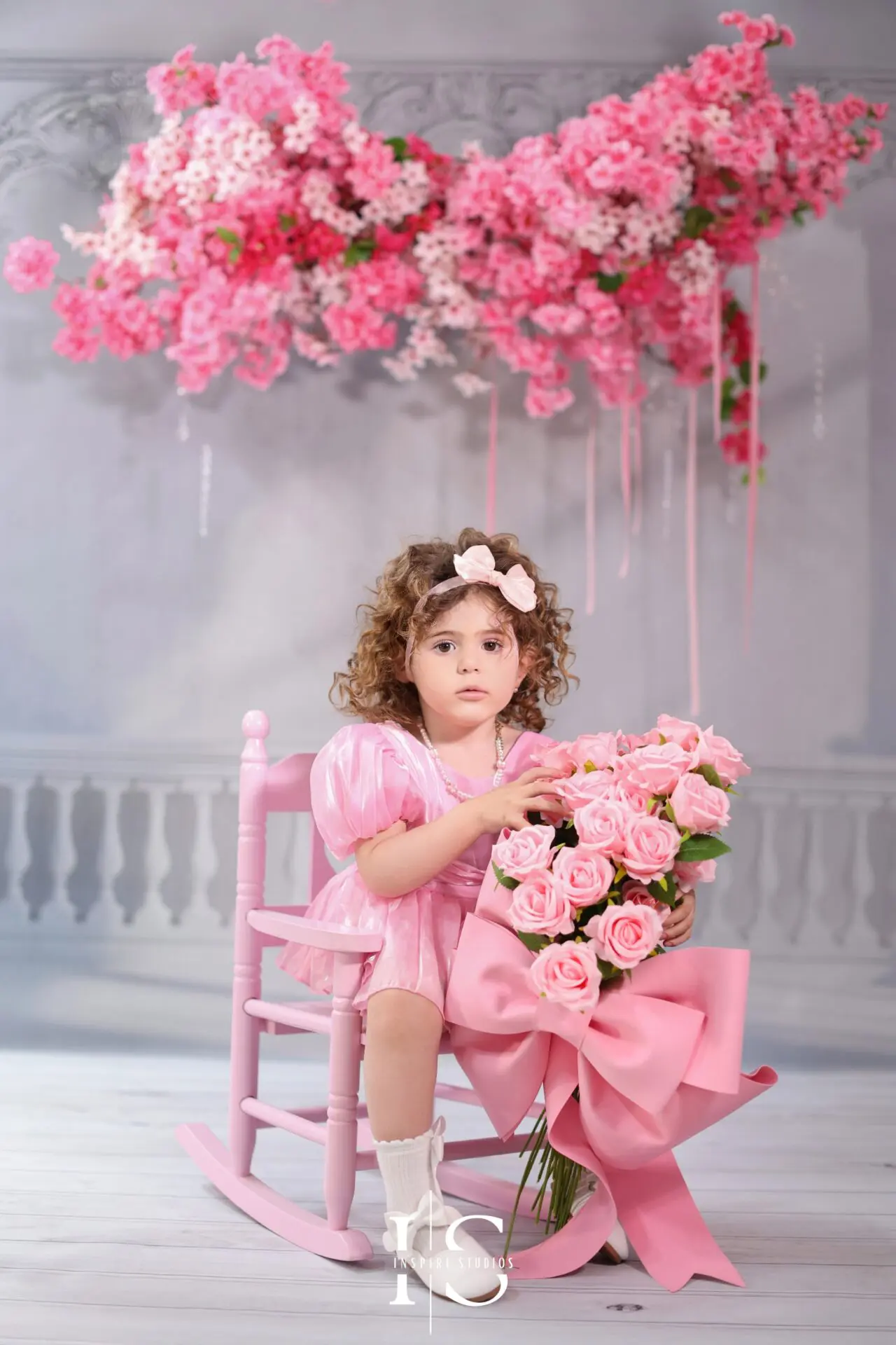 Elegant children’s birthday photoshoot set against a cherry blossom backdrop in an East London studio, featuring soft pink florals, luxury props, and a beautifully dressed child celebrating their special day.