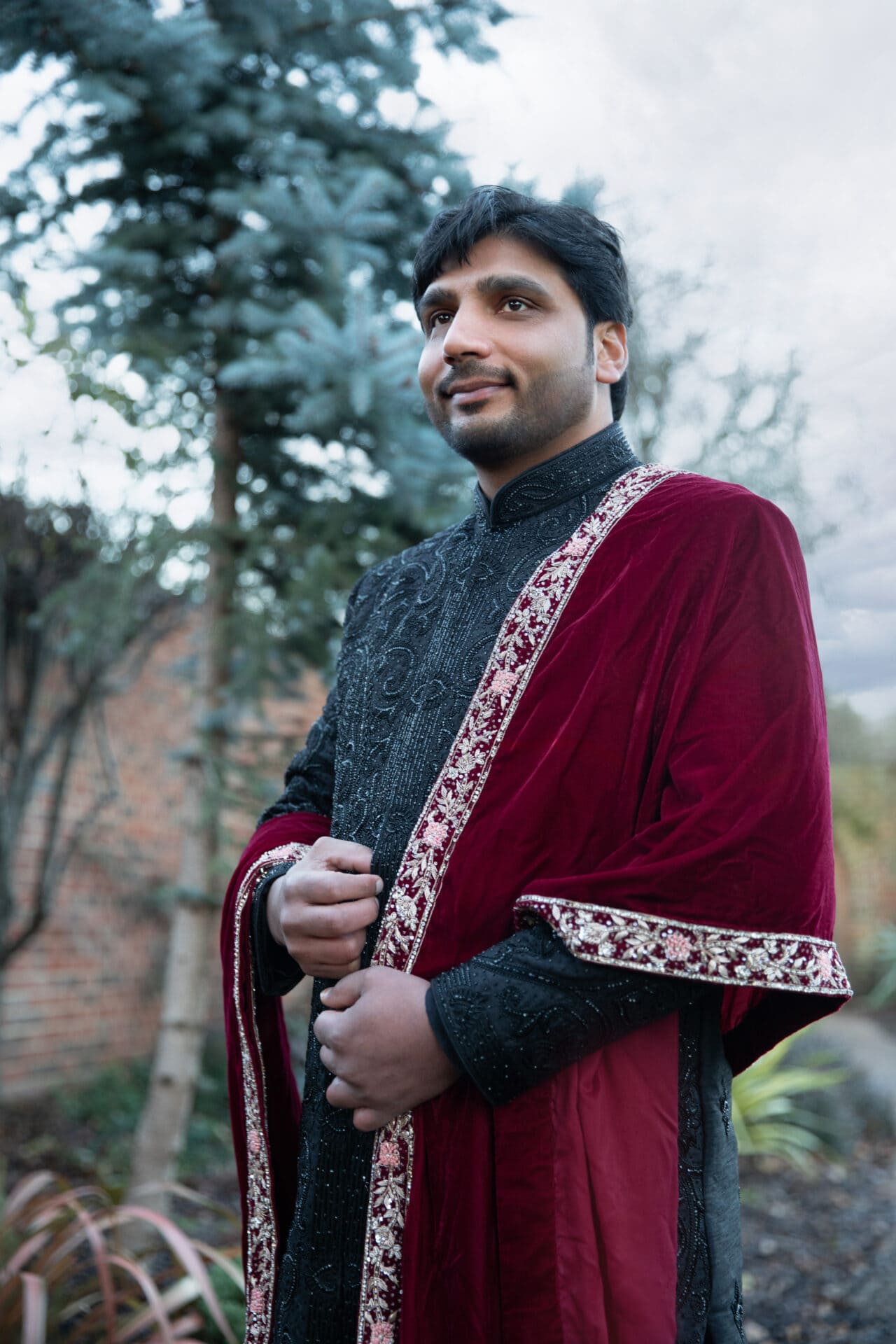 Muslim groom adjusting his sherwani during an outdoor wedding shoot in London.