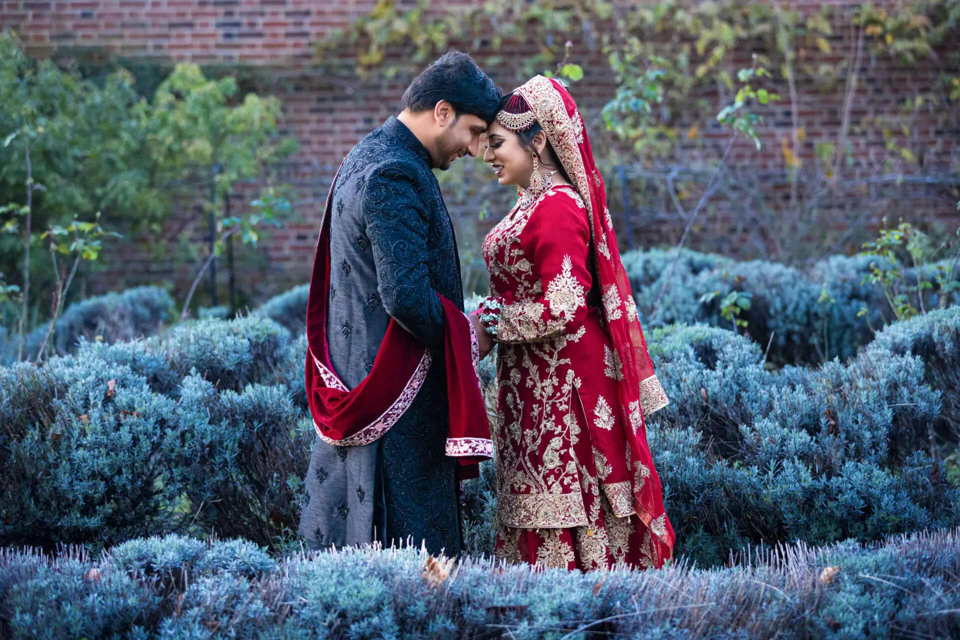 Muslim bride wearing red and gold dress in London park setting