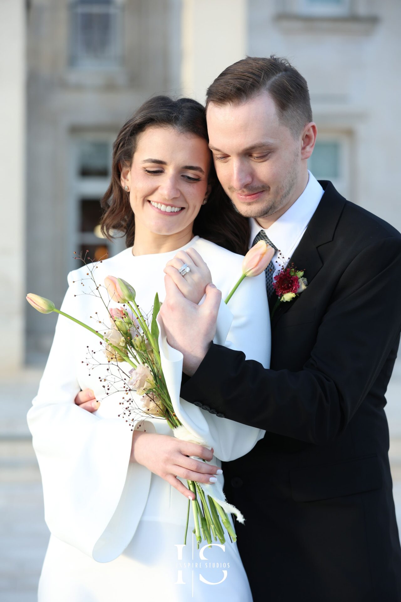 Bride twirls in minimalist dress while groom watches, candid movement shot at London registry venue