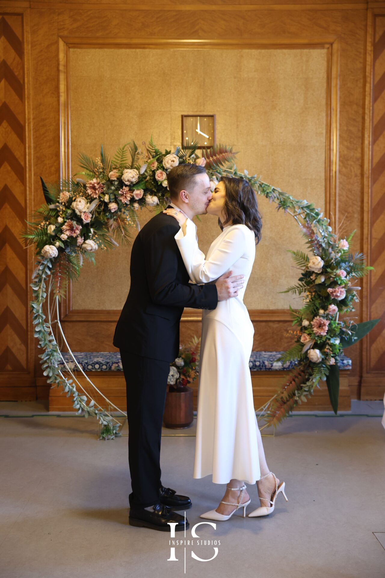 Bride and groom kiss surrounded by smiling guests after London registry wedding at Walthamstow Town Hall