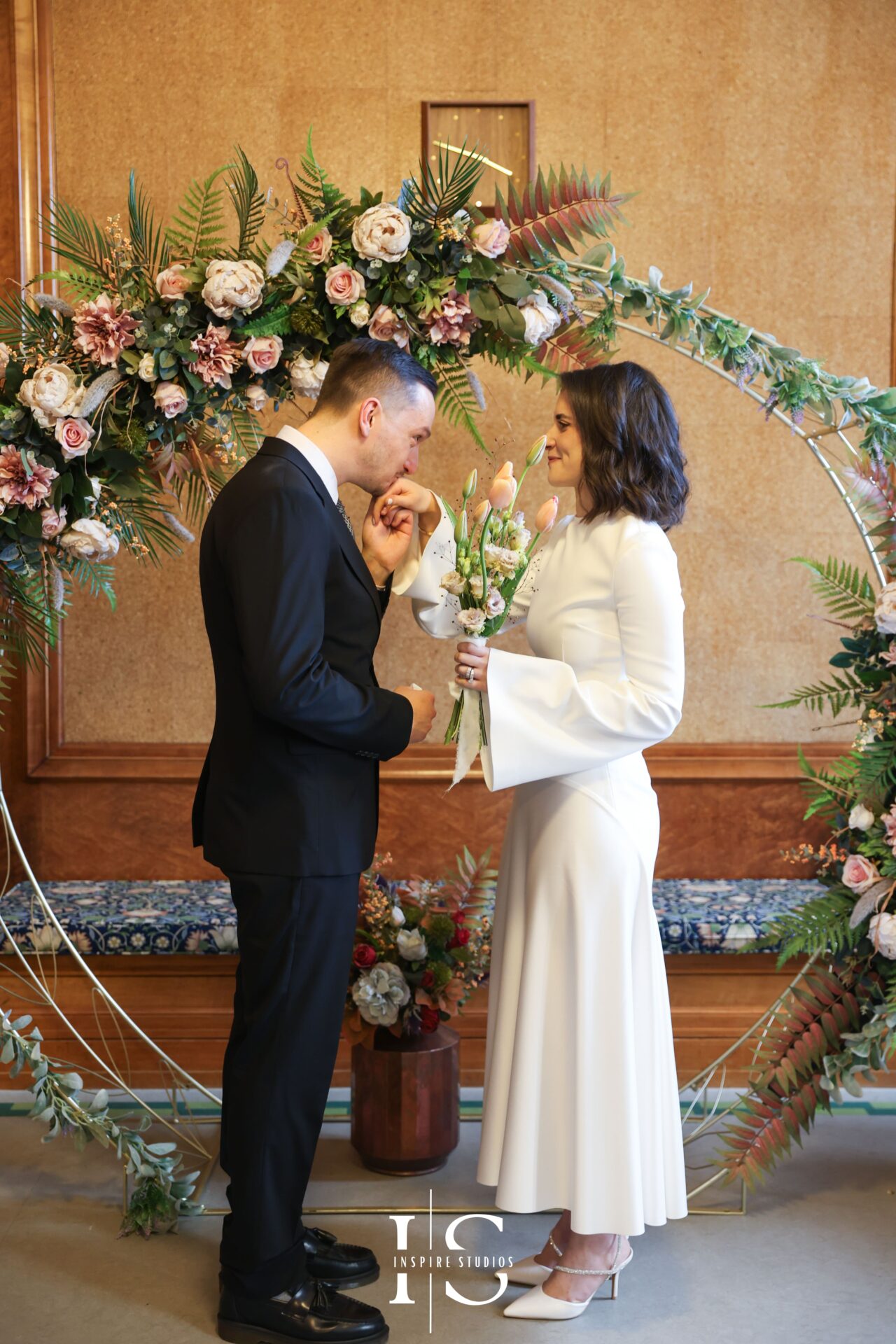 Groom gently kissing bride’s hand during registry wedding