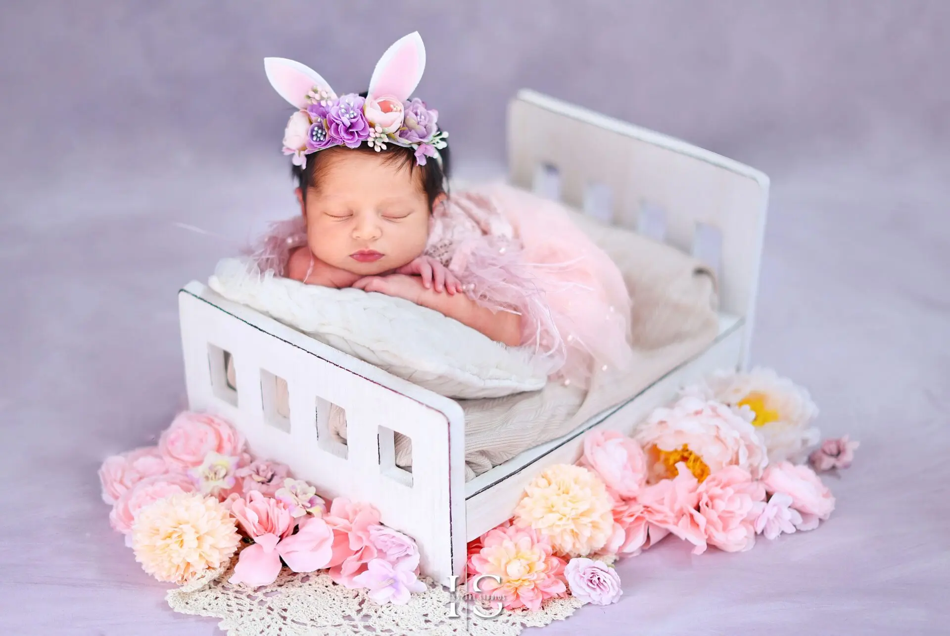 Newborn baby girl sleeping on a pink floral bed with delicate flower decorations
