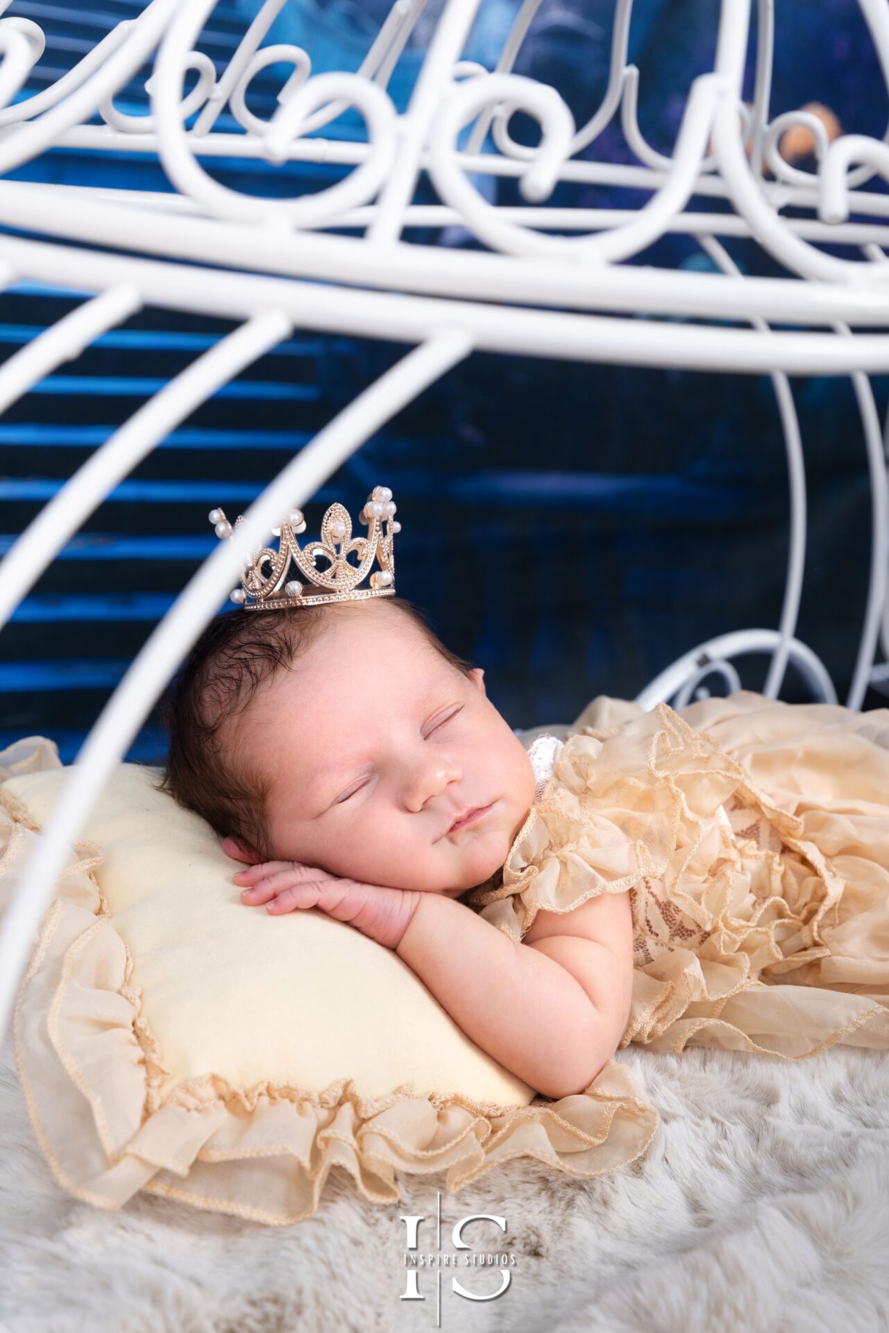 Newborn baby girl dressed in Cinderella-themed outfit lying peacefully in studio