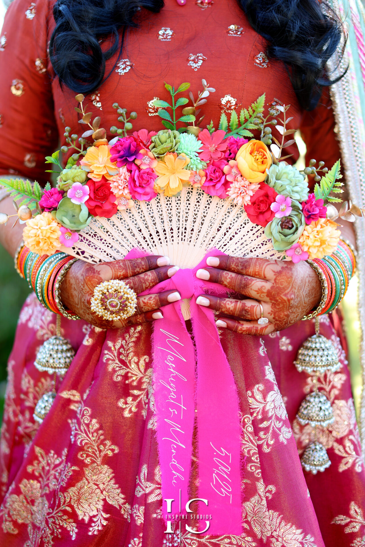 Bride with henna-adorned hands posing under Mehndi décor, captured by a London female photographer.