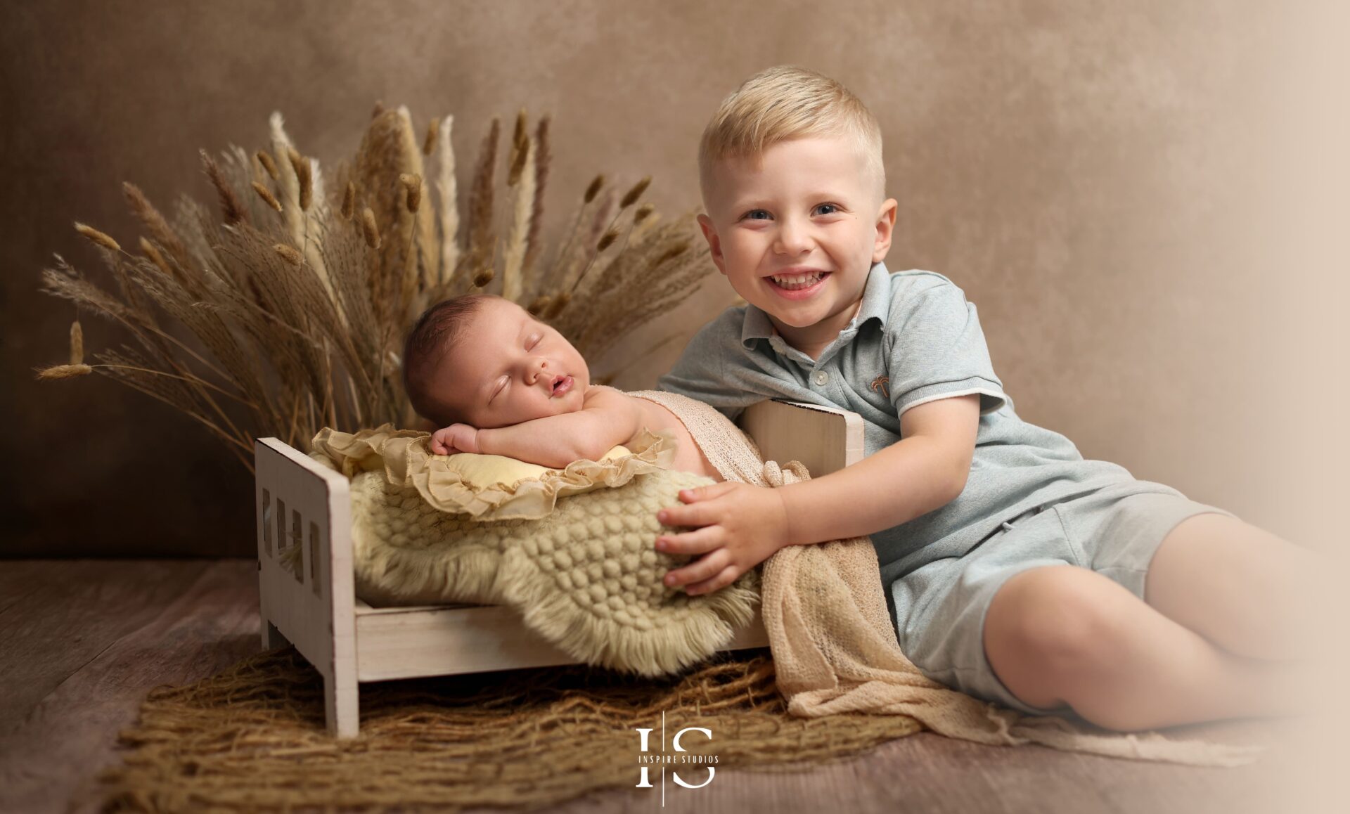 Baby boy in studio photoshoot with cream and wooden textures, part of a family session
