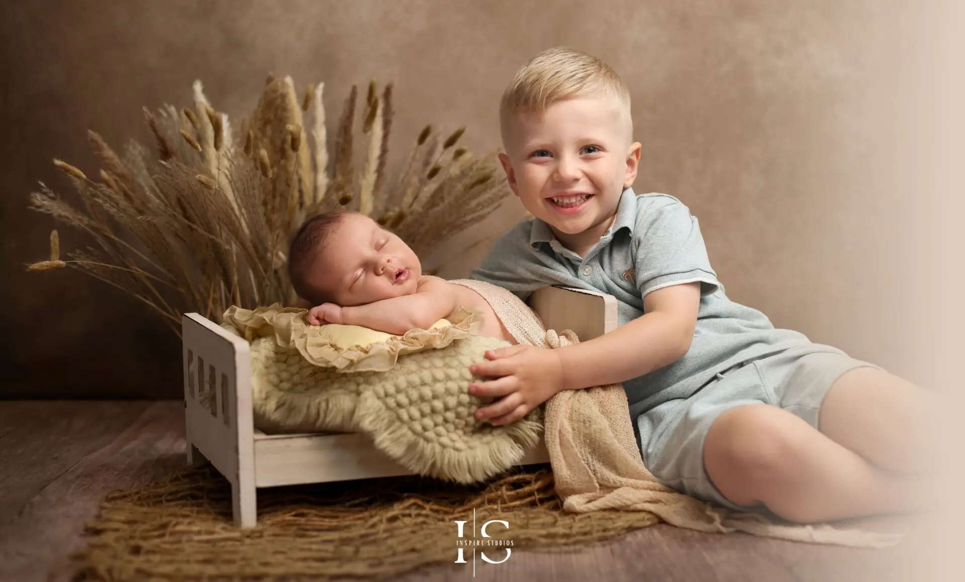 Baby boy in studio photoshoot with cream and wooden textures, part of a family session