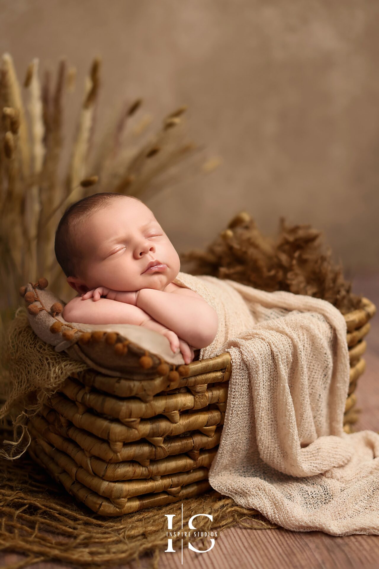 Baby boy sleeping peacefully on a layered cream backdrop during newborn photoshoot