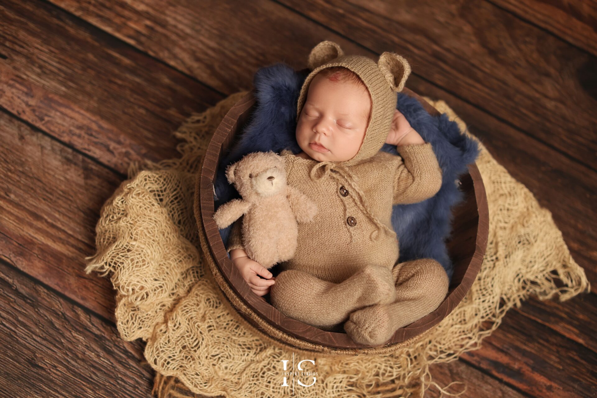 Peaceful newborn baby boy posed in soft, cozy textures during studio photoshoot