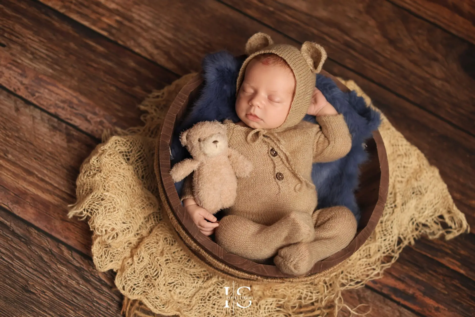 Peaceful newborn baby boy posed in soft, cozy textures during studio photoshoot