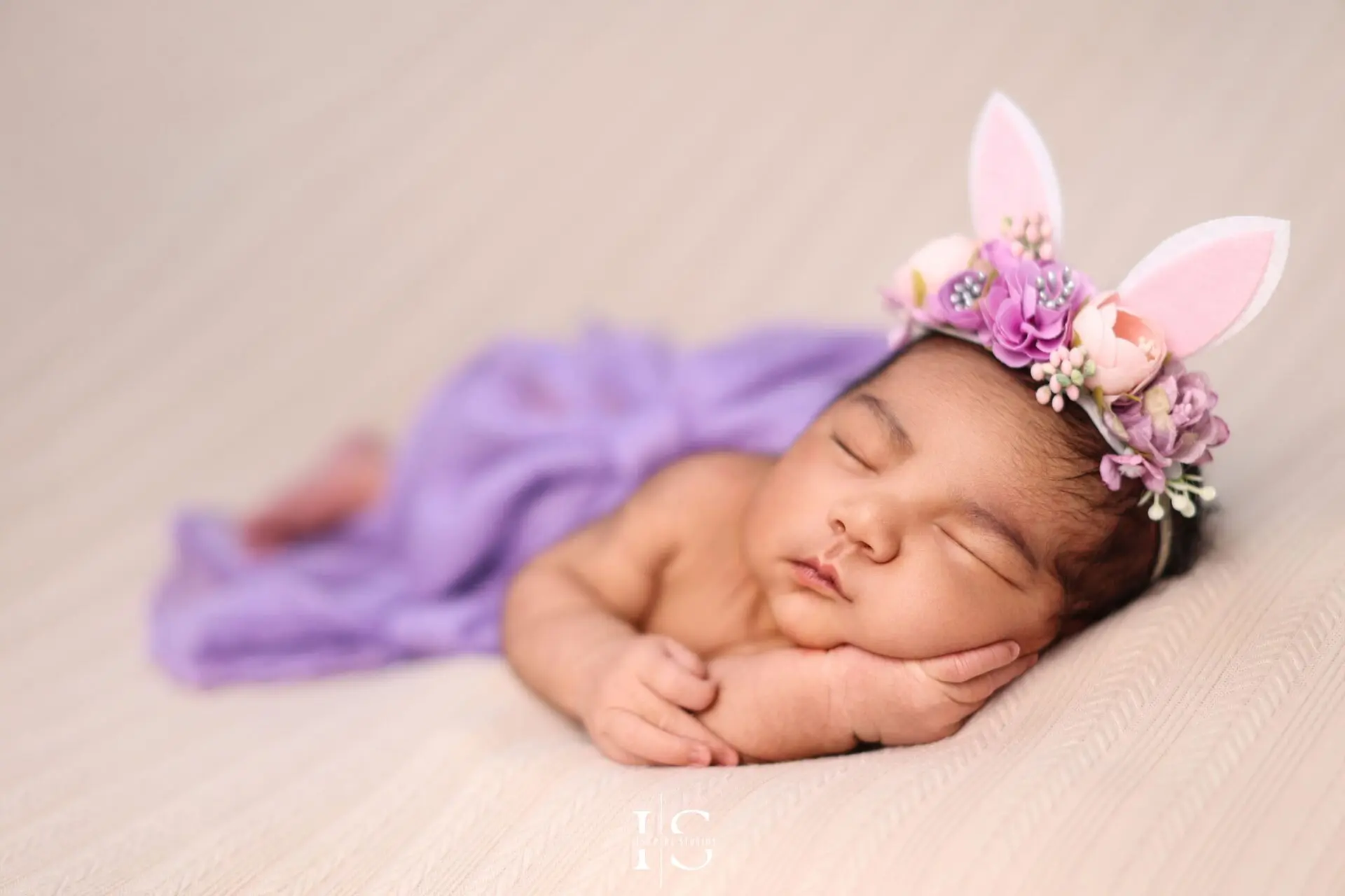 Studio image of a baby girl peacefully posed in a newborn wrap.
