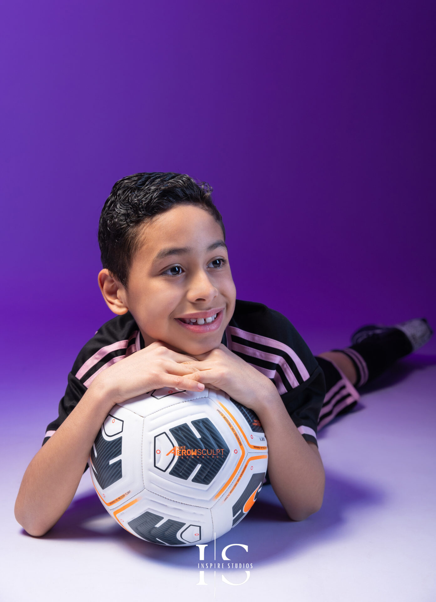 Child posing with a football during a themed studio photoshoot in London.