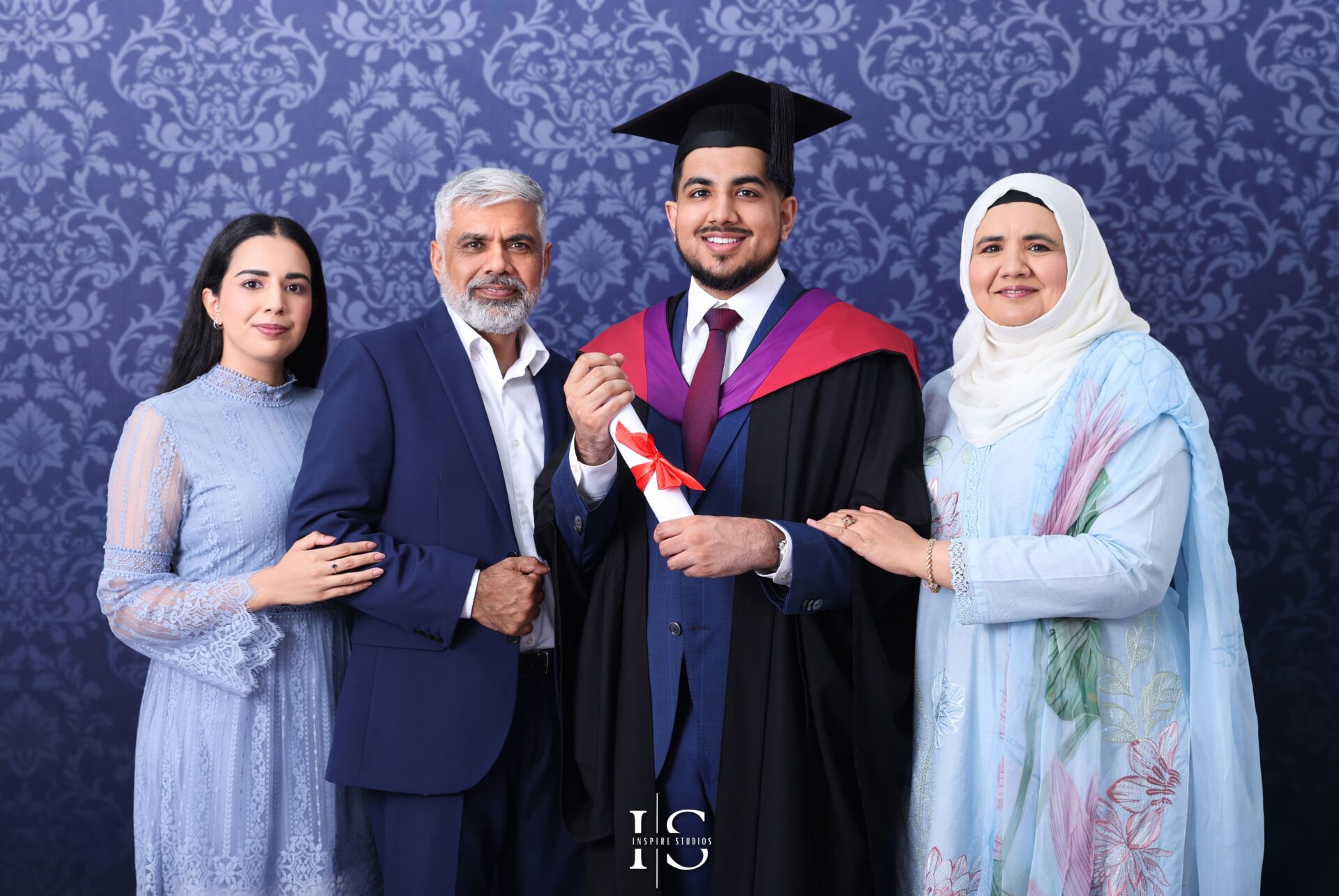 Graduate holding diploma surrounded by family during studio photoshoot