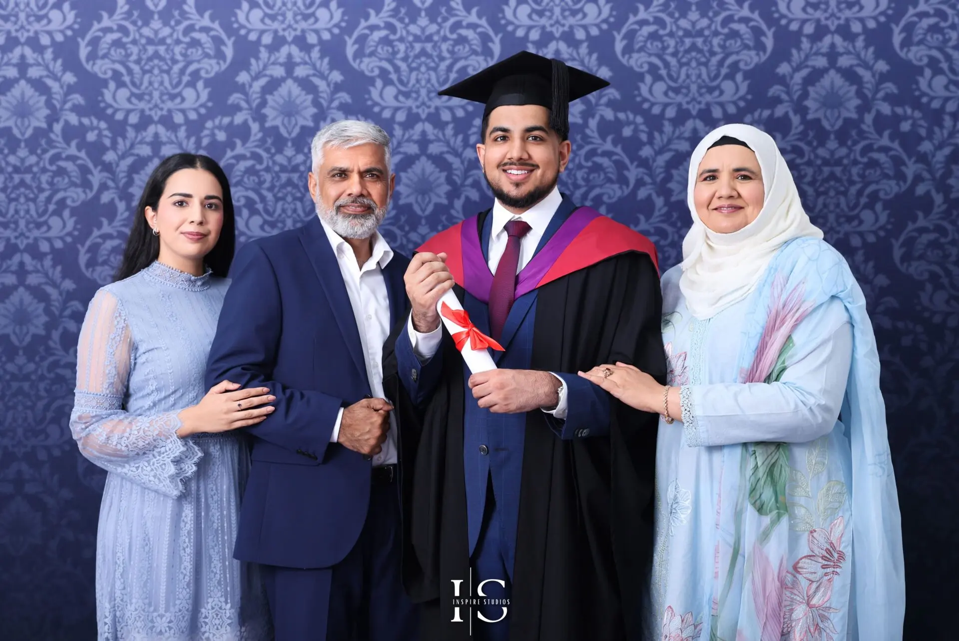 Graduate holding diploma surrounded by family during studio photoshoot