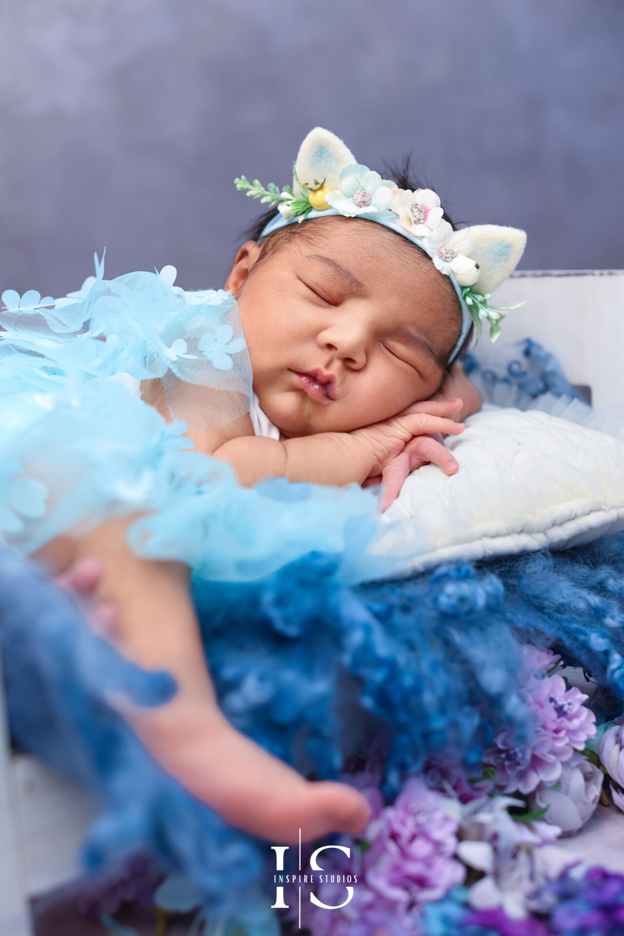 Female newborn photographer gently positioning a baby girl in the studio.
