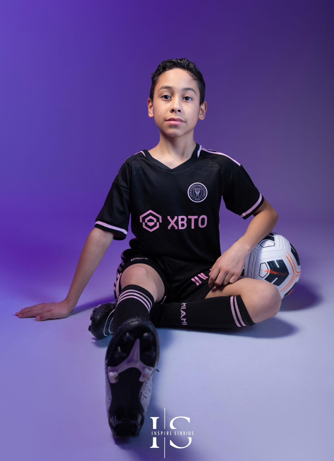 Child smiling and posing with football props in a themed studio photoshoot.