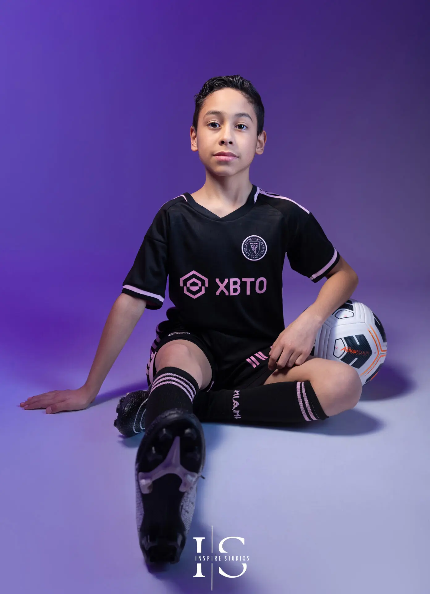 Child smiling and posing with football props in a themed studio photoshoot.