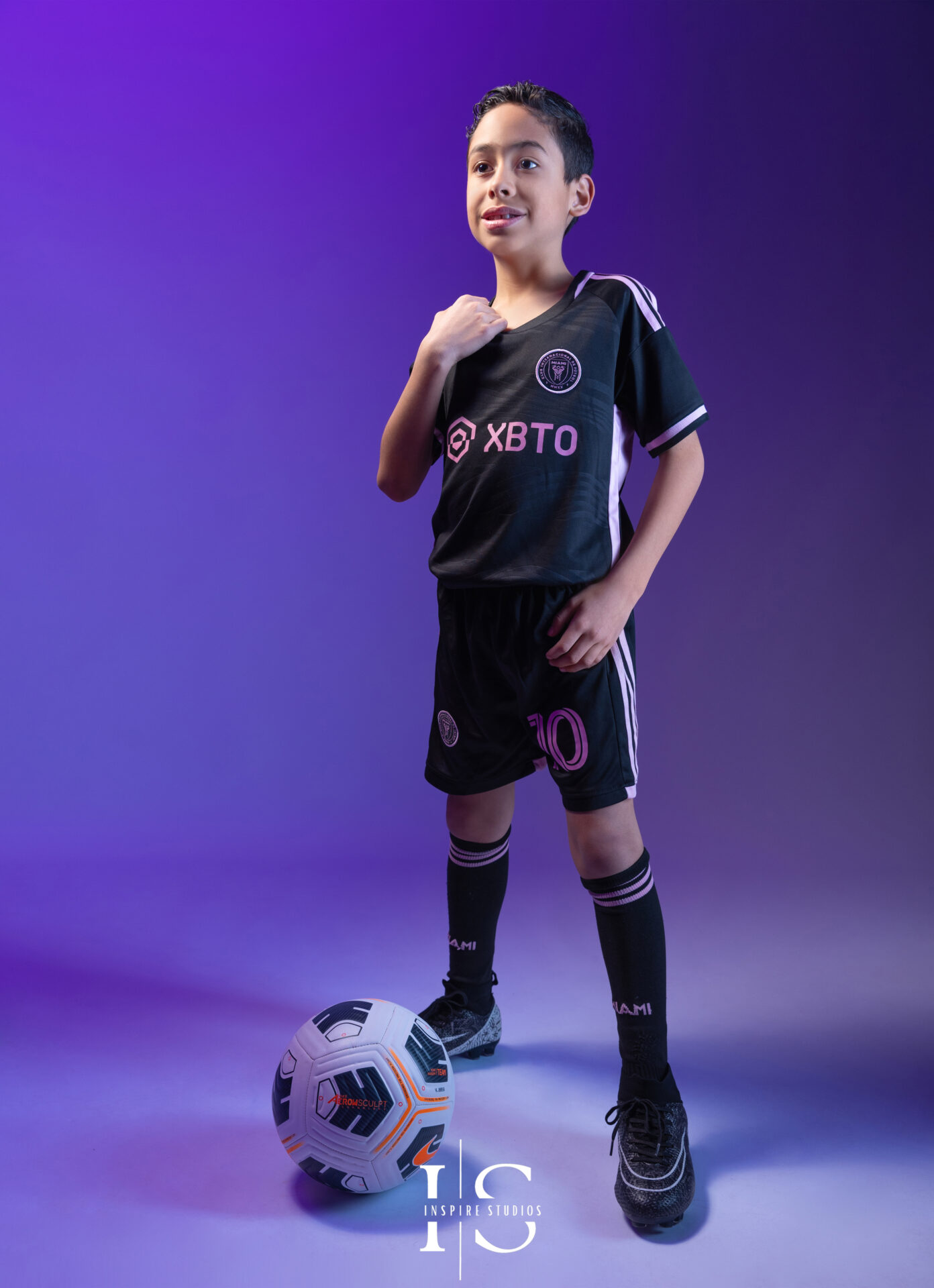 Child holding a football during a studio photoshoot session.